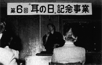 手話落語を演じる小野康二さん。背後は大原省三先生。
